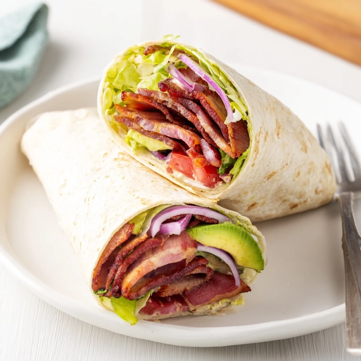 A close-up of a delicious zesty BLT wrap, perfectly rolled and ready to eat, with visible ingredients.