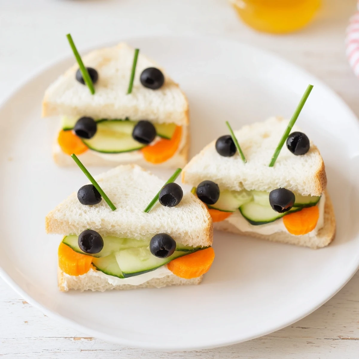 Vibrant board of bee sandwich cutouts with fresh fruits, vegetables, and olives forming playful designs.