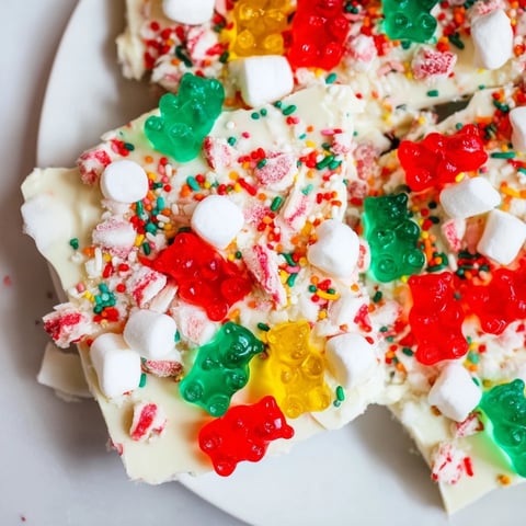 White chocolate bark topped with colorful gummy bears and candy canes, a delightful sweet treat.