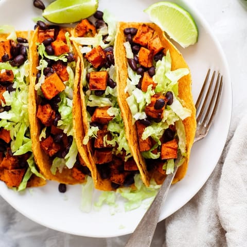 Homemade Sweet Potato Black Bean Tacos, ready to eat with a tangy lime garnish.
