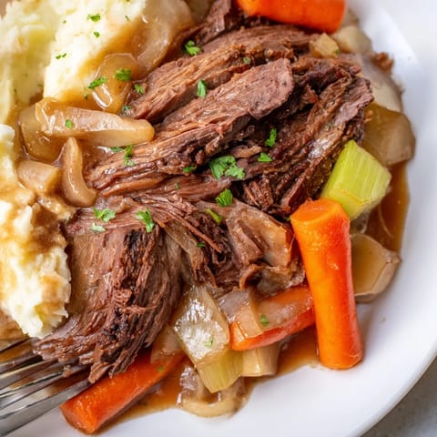 Tender slow cooker pot roast served with creamy mashed potatoes and fresh herbs.  