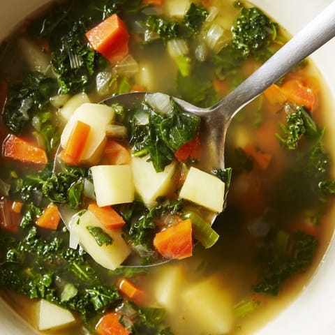 Close-up of a rustic bowl filled with Vegetarian Potato-Kale Soup, garnished, inviting a cozy dinner.