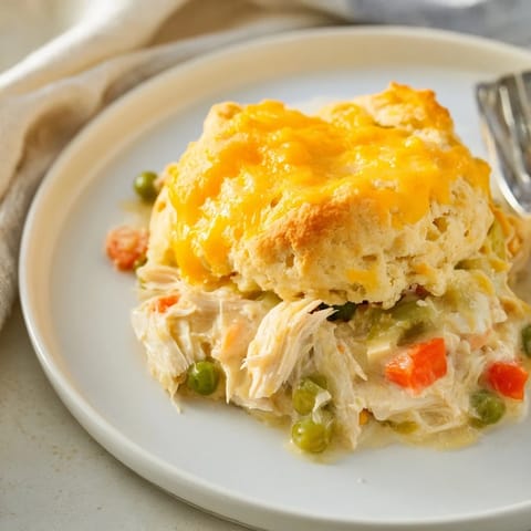 Golden, cheesy biscuits sit atop a bubbling One-Pan Chicken Cobbler with visible vegetables.