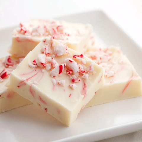 This decadent White Chocolate Peppermint Bark Fudge appears rich, with a swirled peppermint top.