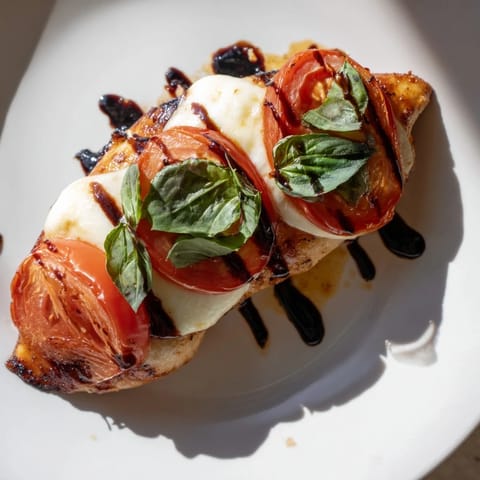 Golden seared chicken breasts in a Caprese Chicken Skillet, topped with bubbling mozzarella and drizzled with balsamic glaze.