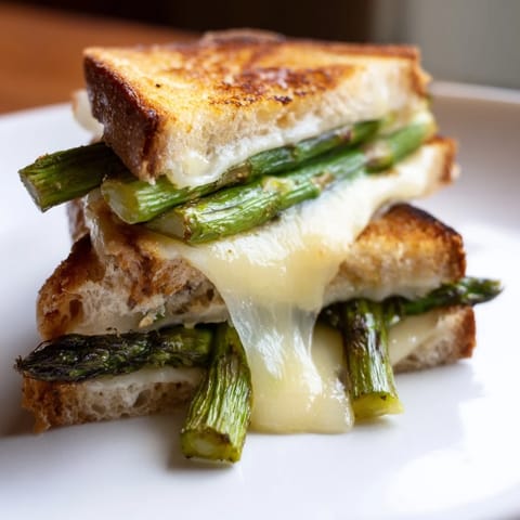 Creamy Brie and charred asparagus spears peek out from crispy buttery bread, perfect for a light lunch or dinner pairing.