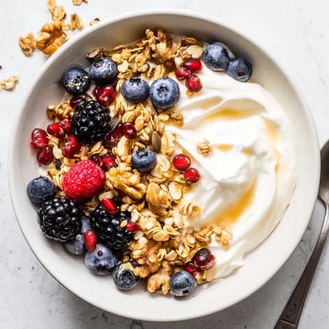 A vibrant Yogurt Bowl with Winter Berries and Spiced Crunch, topped with juicy cranberries and pomegranate seeds.