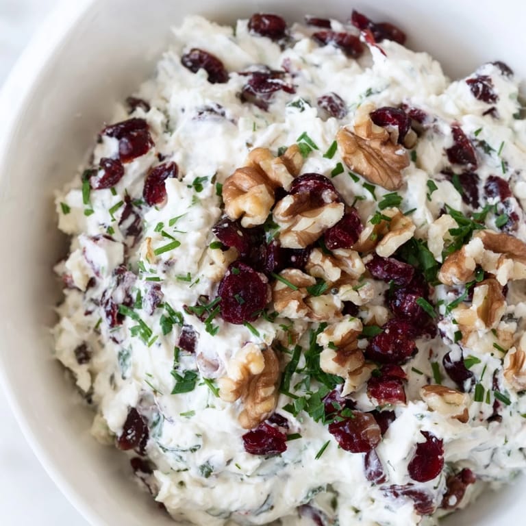 This Lightened Holiday Cream Cheese Dip is a festive appetizer, garnished with fresh herbs and cranberries.