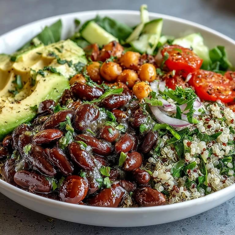 Hearty Three-Bean Power Bowl combining black beans, chickpeas, and quinoa, drizzled with Dijon vinaigrette and fresh herbs.